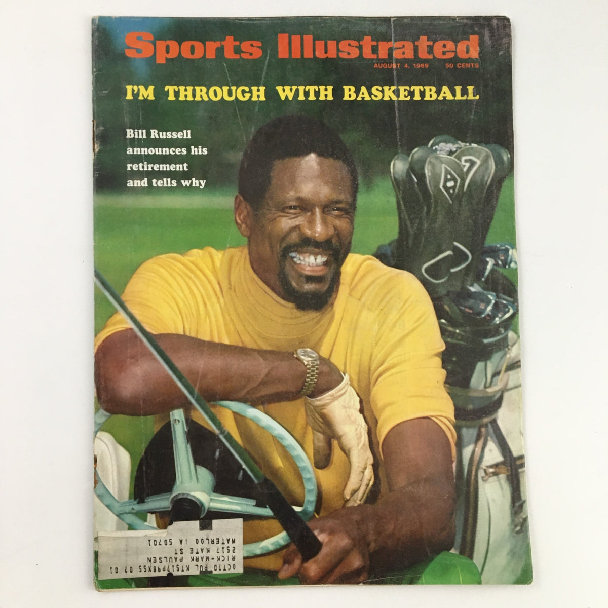 Cover of Sports Illustrated Magazine August 4, 1969 featuring Bill Russell with the headline 'I'm Through With Basketball'. The iconic magazine showcases Russell smiling, dressed in a yellow shirt, with golf clubs and a golf cart in the background, commemorating his retirement announcement.