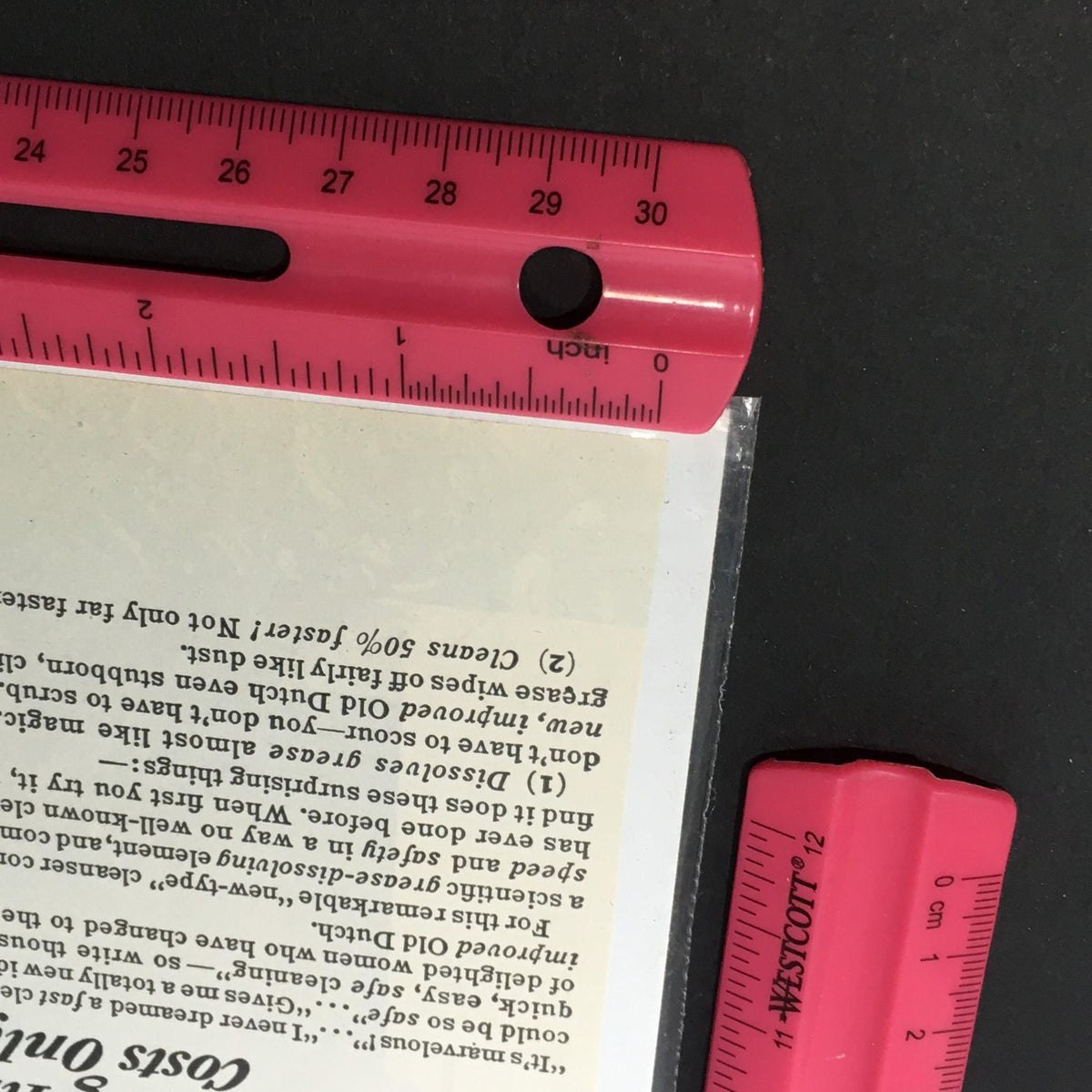 Close-up of the corner of the VTG 1940 Old Dutch Cleanser Made with Seismotite advertisement, featuring a ruler indicating size and showcasing meticulous preservation.