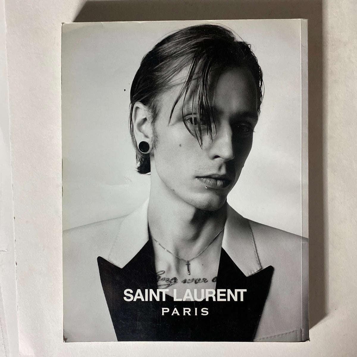 Hero Men Fashion Magazine 2015 cover showcasing a black and white portrait of a male model with an elegant hairstyle, wearing a Saint Laurent outfit and earrings, symbolizing modern fashion.
