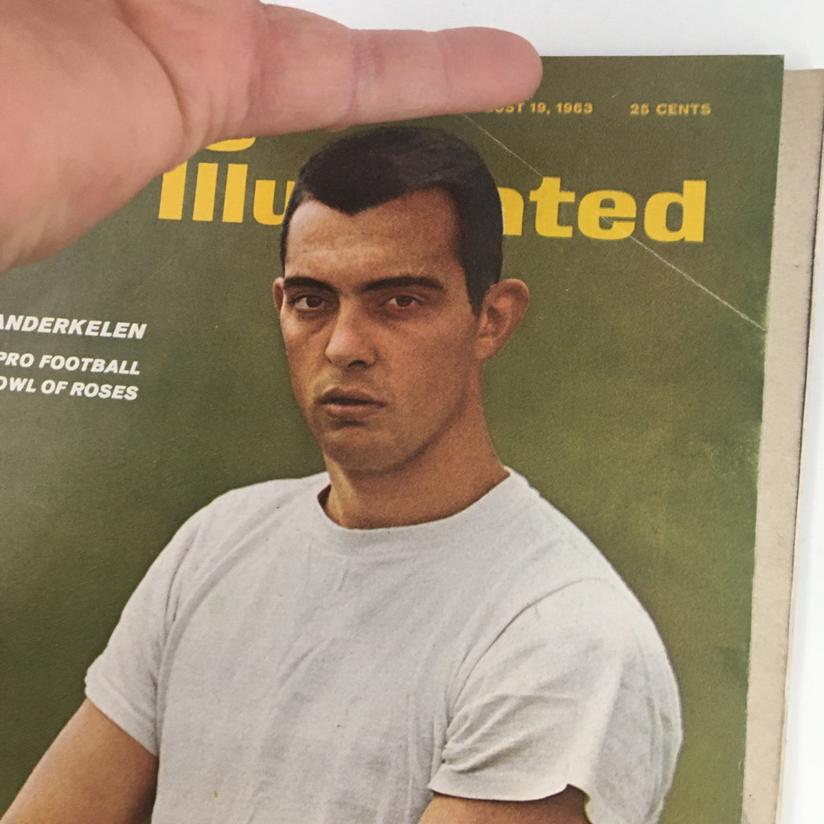 Close-up of the Sports Illustrated Magazine August 19 1963 cover, highlighting quarterback Ron Vander Kelen's serious expression while holding a football.