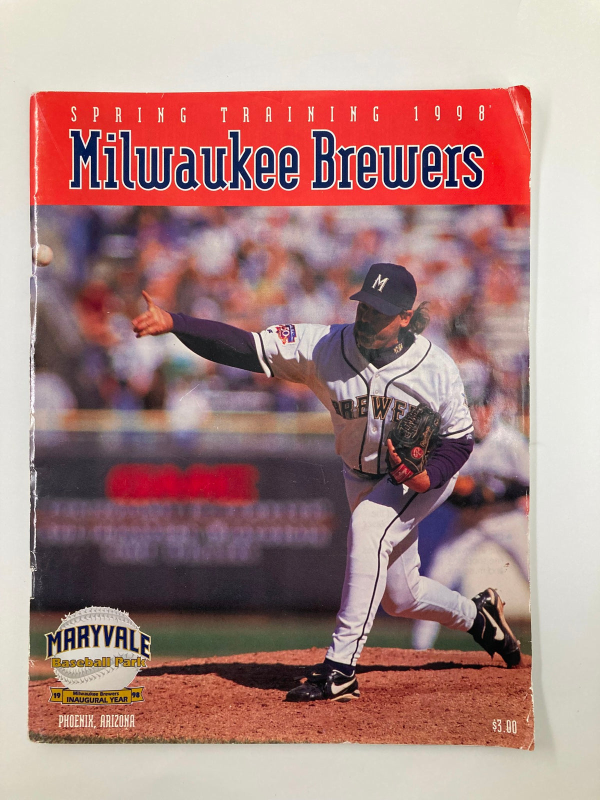 1998 MLB Milwaukee Brewers Official Spring Training Program cover showcasing a pitcher in action during practice, highlighting the team's branding and theme.