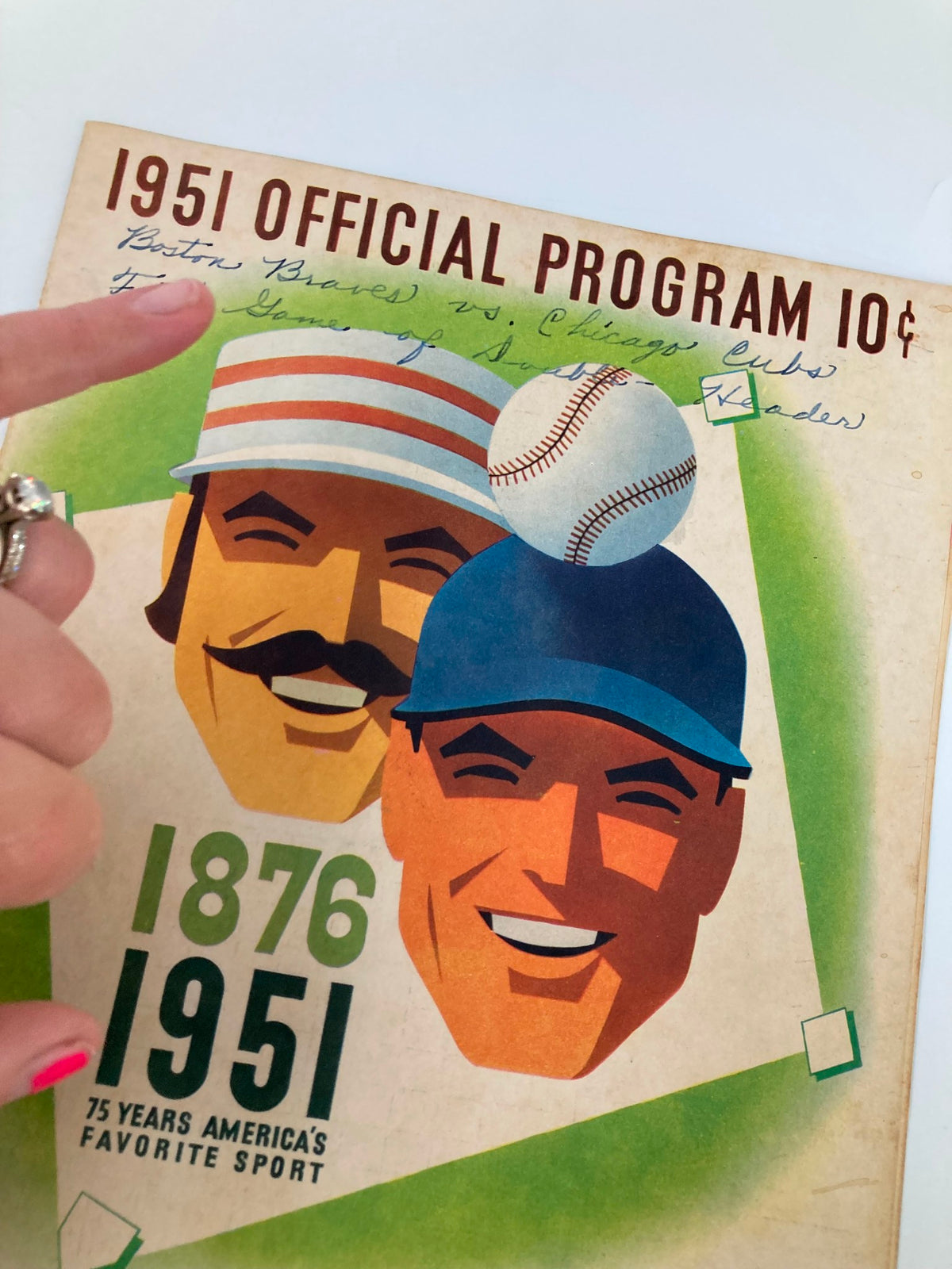 Close-up view of the 1951 MLB Chicago Cubs vs Boston Red Sox Official Program cover showing handwritten details about the game and the smiling faces of two baseball players.