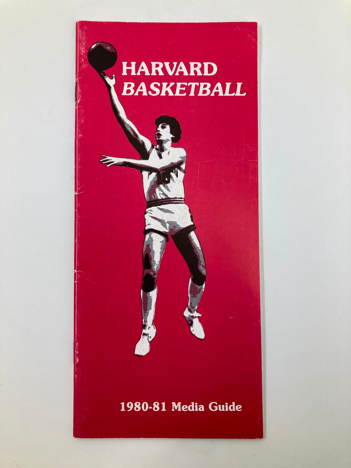 Cover of the 1980-1981 NCAA Harvard Crimson Basketball Official Media Guide featuring a player in action on a pink background.