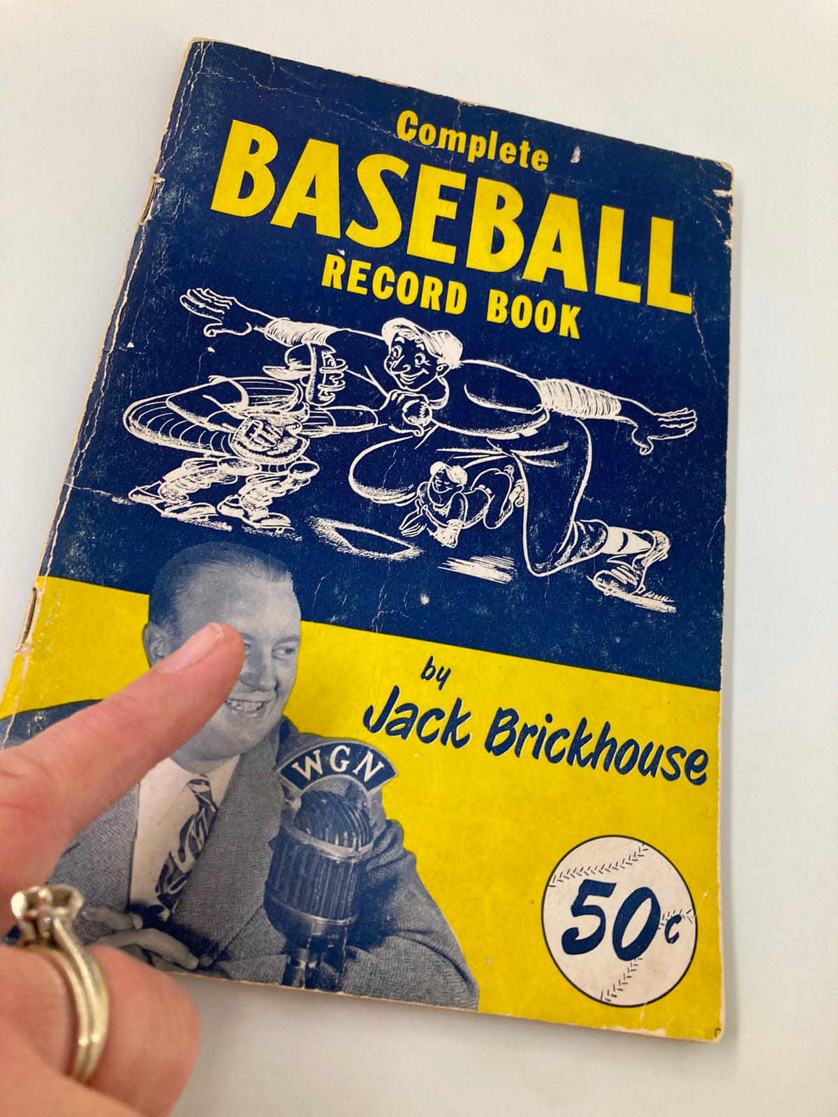 Detailed view of the 1950 Jack Brickhouse Complete Major League Baseball Record Book cover, highlighting illustrations and the author's name, reflecting the charm of vintage baseball collectibles.