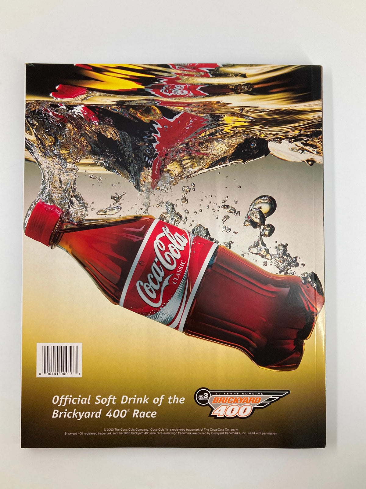 August 3 2003 NASCAR 10 Years Running Brickyard 400 Official Program back cover showcasing a Coca-Cola bottle, prominently featuring the branding as the Official Soft Drink of the Brickyard 400 Race.