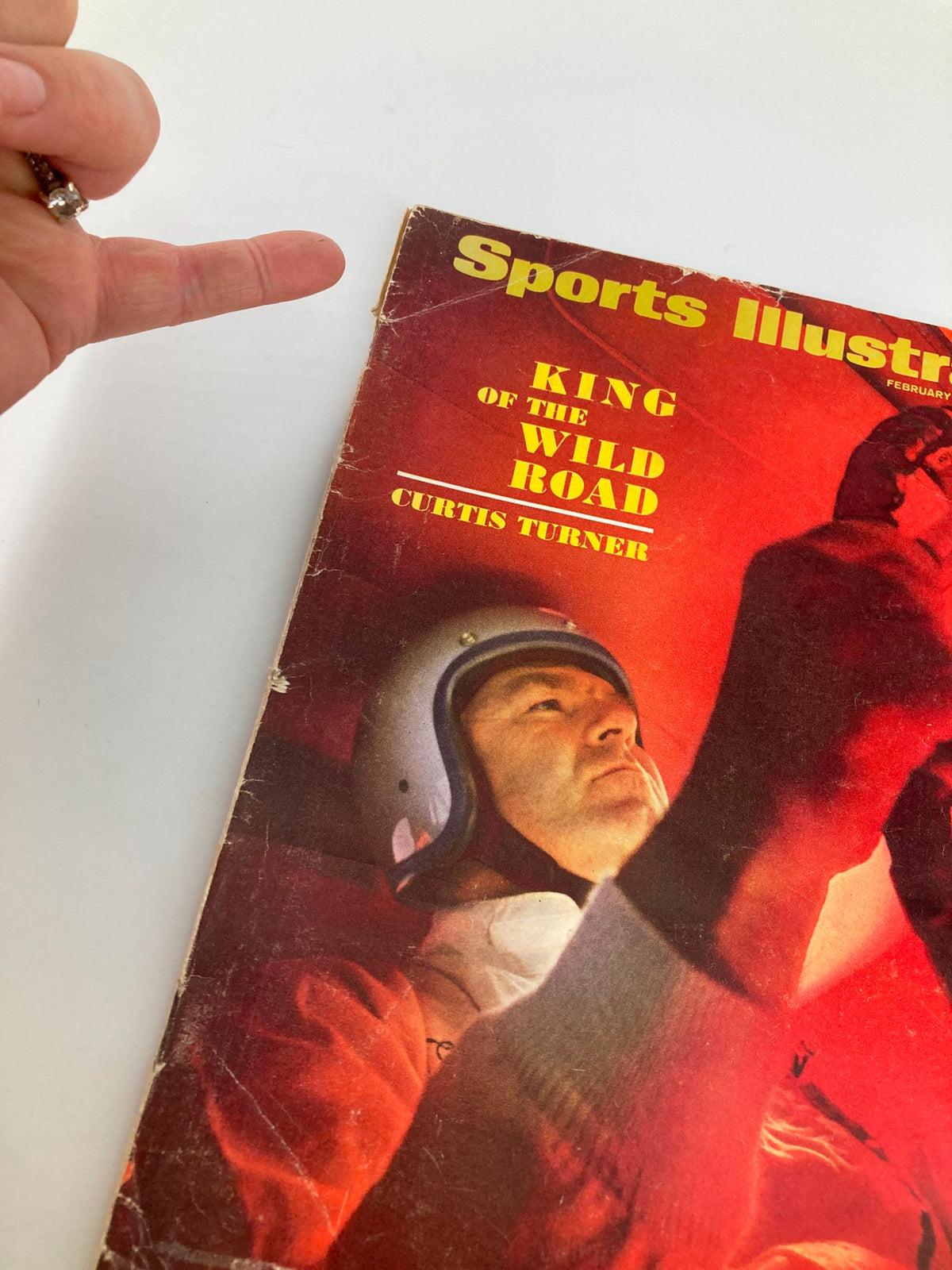 Close-up of the cover of Sports Illustrated Magazine from February 26, 1968, showcasing Curtis Turner, King of Wild Road, with a hand indicating the title.