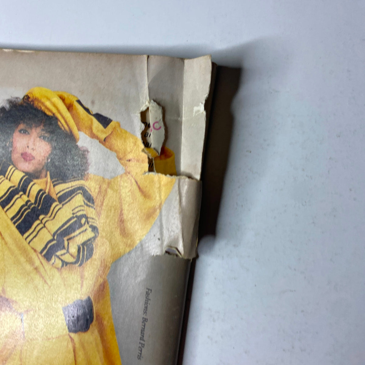 Close-up view of Virginia Slims advertisement from the back cover of Ebony Magazine January 1987 Vol 42 No. 3, featuring a model in yellow, highlighting minor damage on the advertisement.