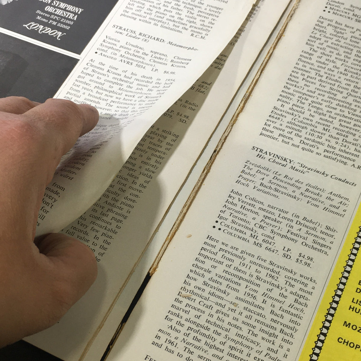 Hand flipping through pages of VTG High Fidelity Music Magazine February 1965, revealing content related to music reviews, encapsulating the magazine's historical significance.