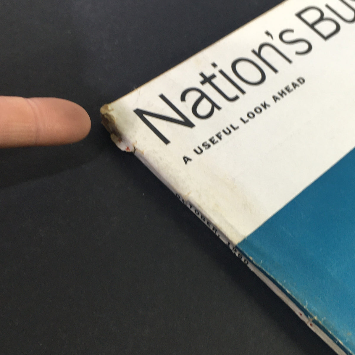 Close-up view of the spine of VTG Nation's Business Magazine October 1960, showing wear and tear indicative of its vintage condition, while maintaining its historical significance.