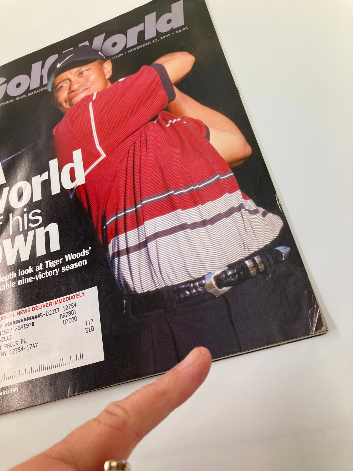Close-up of the cover of Golf World Magazine from November 12, 1999, Volume 53 Issue 21 showcasing Tiger Woods, with focus on the headline 'A World of His Own' and details about his nine-victory season.