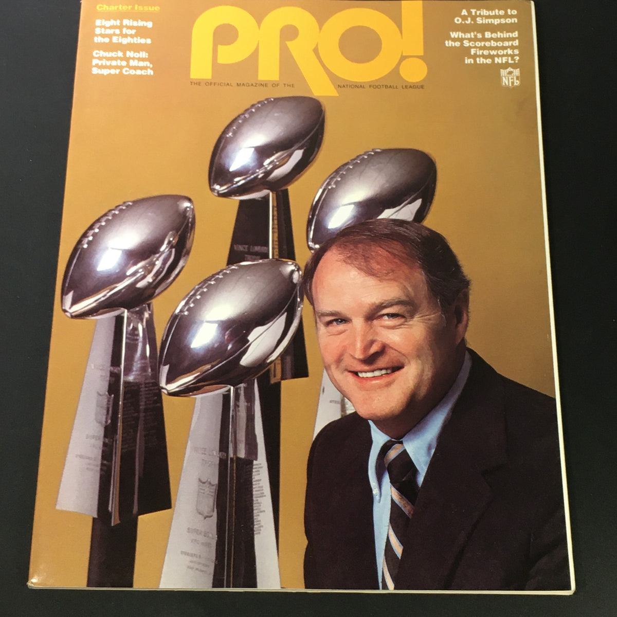 1981 NFL Pro Magazine Charter Issue featuring a tribute to Coach Chuck Noli and O.J. Simpson, showcasing the magazine cover with shiny Vince Lombardi trophies and Coach Chuck Noli smiling.