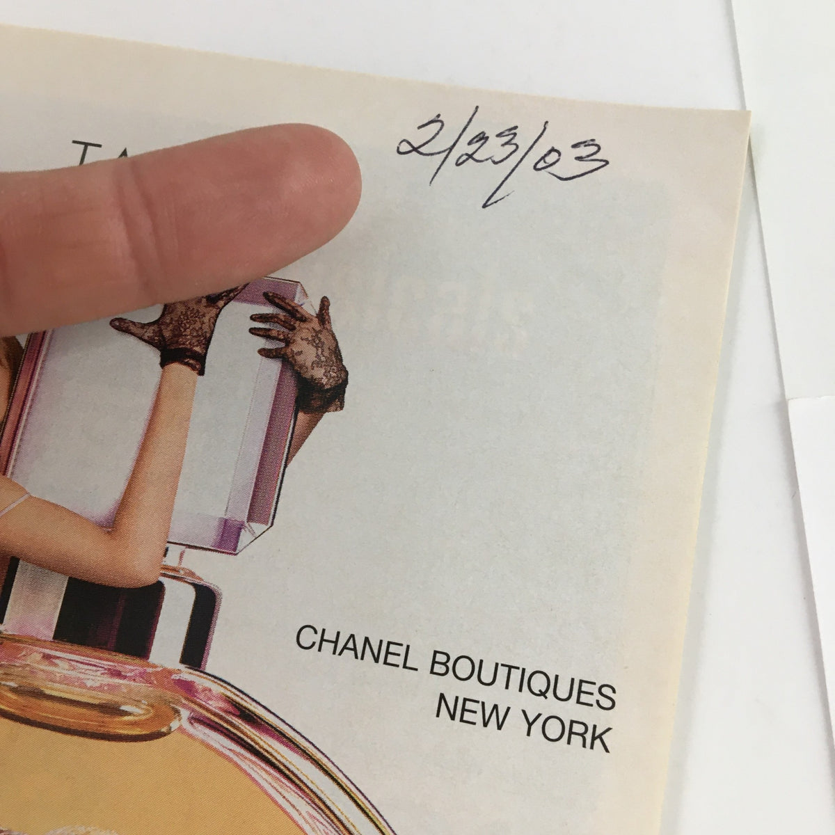 Close-up of a hand pointing at the date on a vintage 2003 Playbill for Rodgers & Hammerstein's Oklahoma! from Gershwin Theatre, featuring Chanel Boutiques New York details.