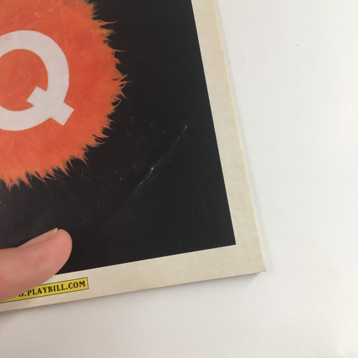 Cover detail of the 2004 Playbill for Avenue Q at the Golden Theatre featuring a furry orange circle with the letter Q, representing the unique style of the acclaimed musical.