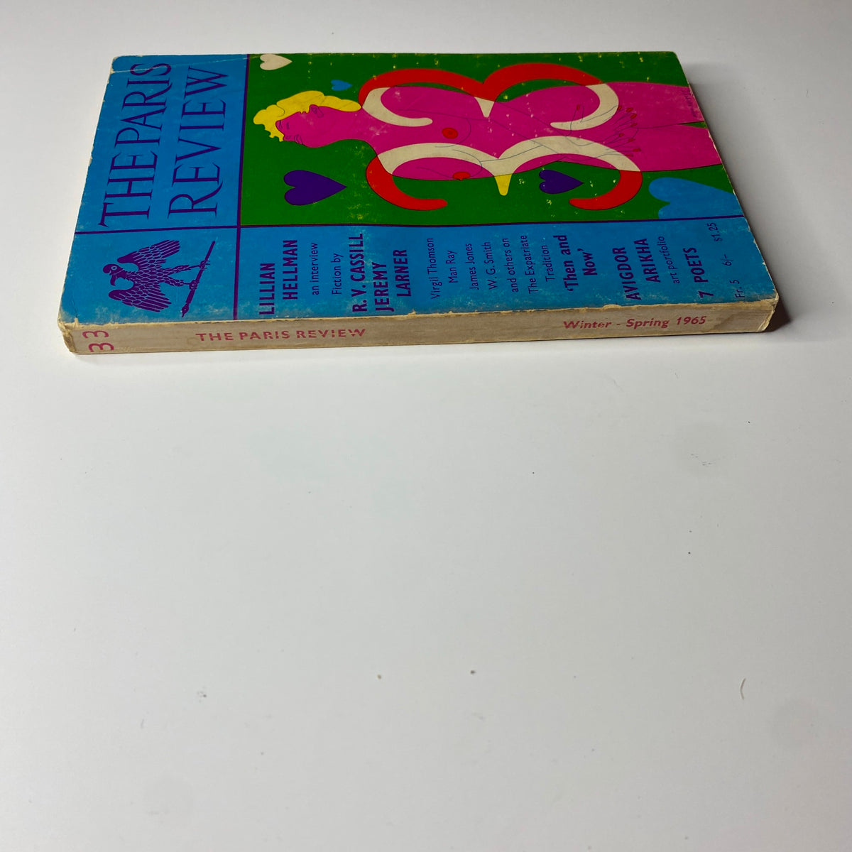 Side view of The Paris Review Magazine Winter-Spring 1965 No. 33, showcasing the colorful spine and cover art with details about the featured authors and themes.