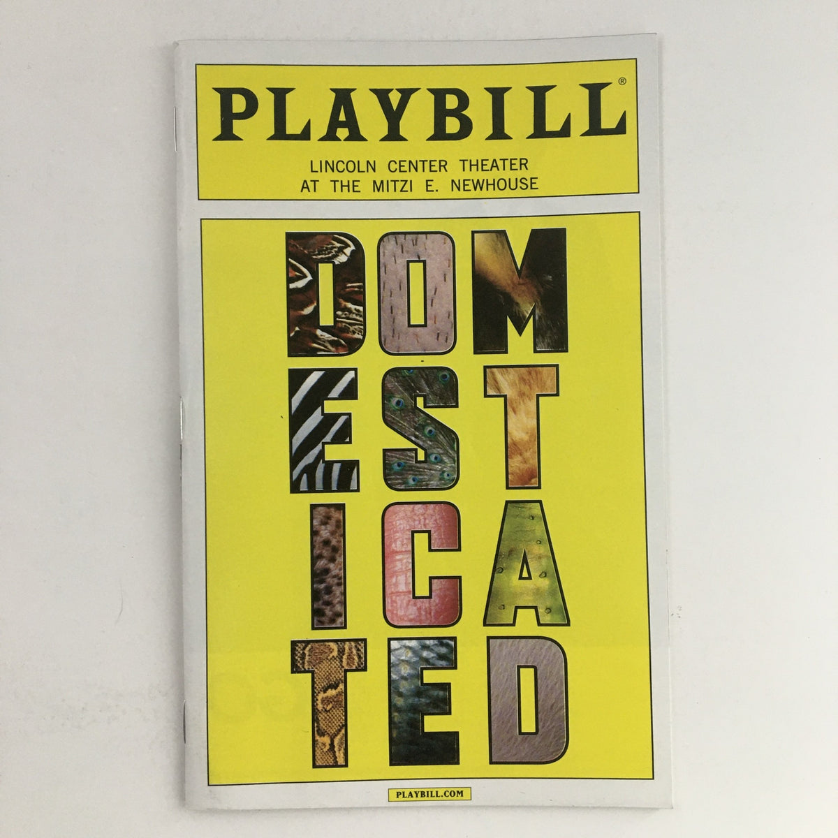 Cover of the 2013 Playbill for Lincoln Center Theater's presentation of 'Domesticated' by Bruce Norris, displaying the title in bold letters with a vibrant yellow background.