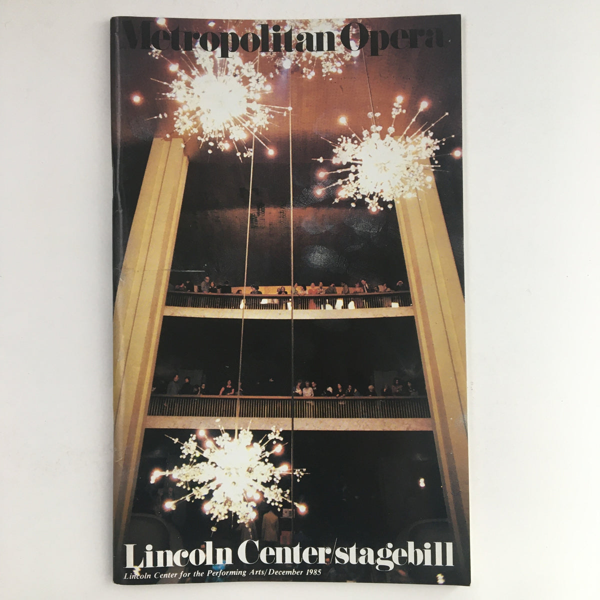 1985 Lincoln Center Stagebill for Metropolitan Opera featuring a stunning interior photograph of the performance venue, showcasing chandeliers and an audience.
