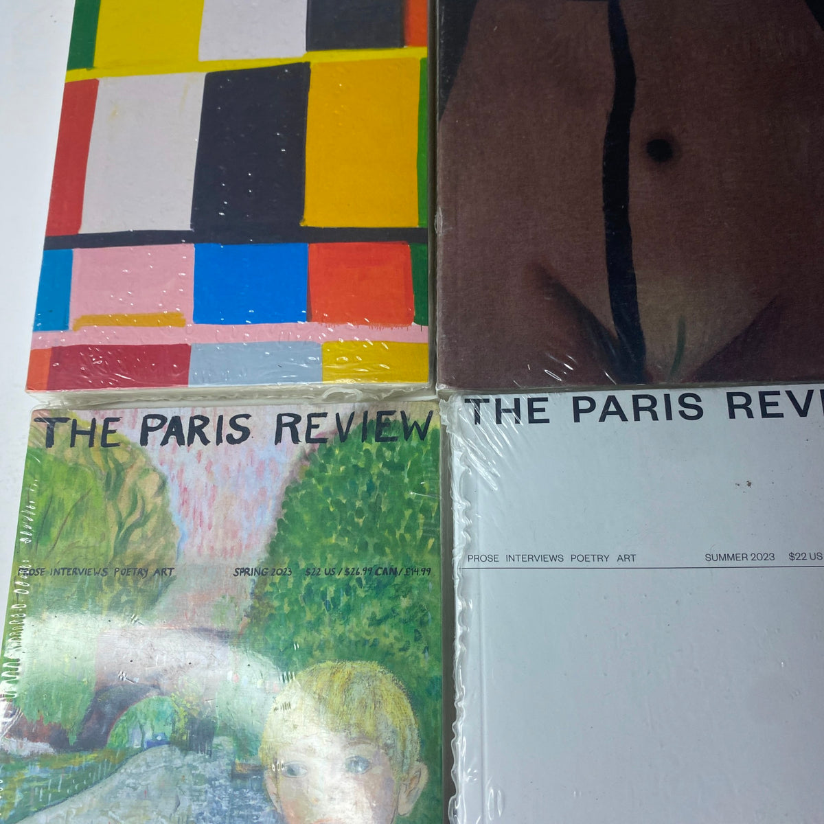 Close-up of The Paris Review Magazine covers showcasing vibrant artwork and sealed packaging for the Winter and Spring 2022-2023 issues.