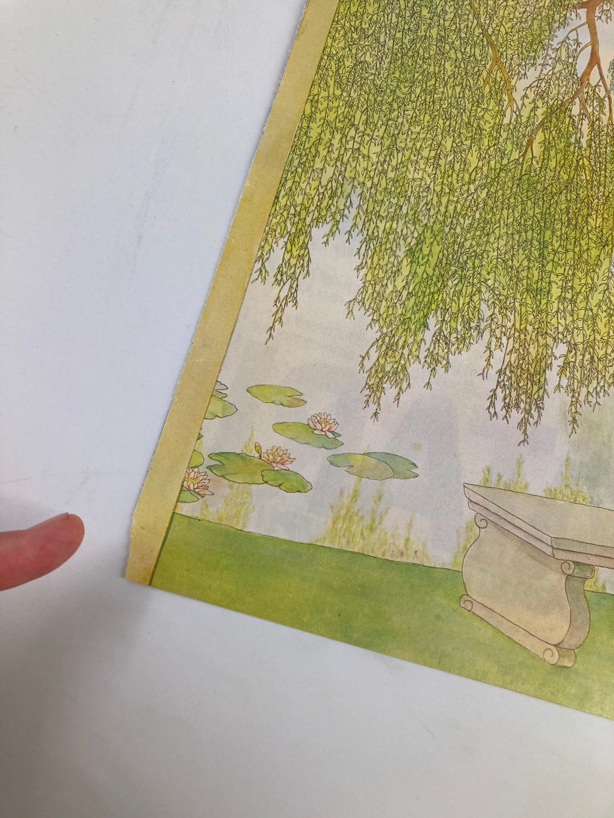 A close-up view of the cover of The New Yorker May 30, 1983, 'Picnic by the Lake' by Jenni Oliver, highlighting details of the artwork, including the bench and surrounding foliage.