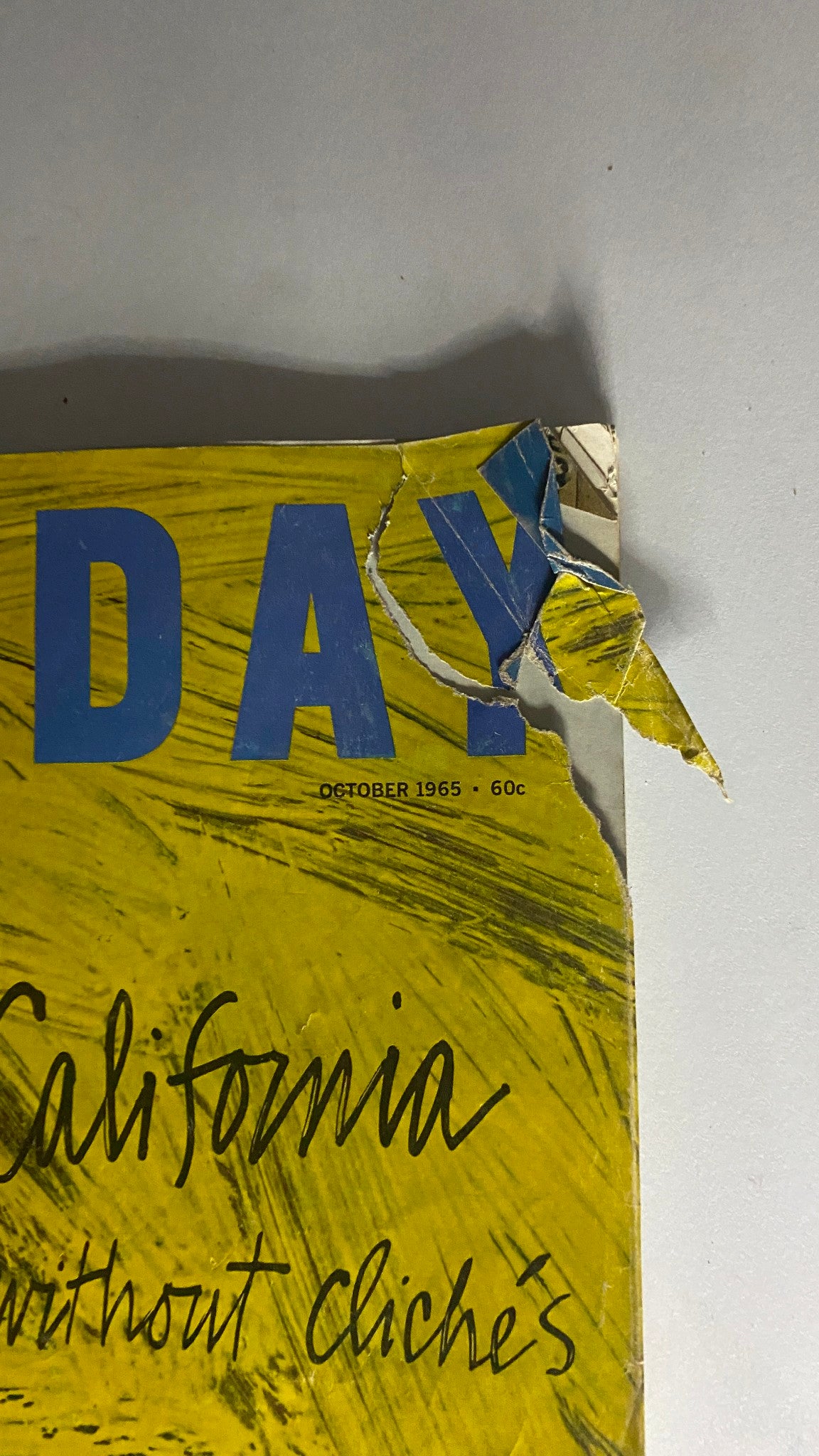 Close-up of the cover of VTG Holiday Magazine October 1965 showing the title 'HOLIDAY' and the subtitle 'California without cliches', highlighting wear and tear typical of vintage magazines.