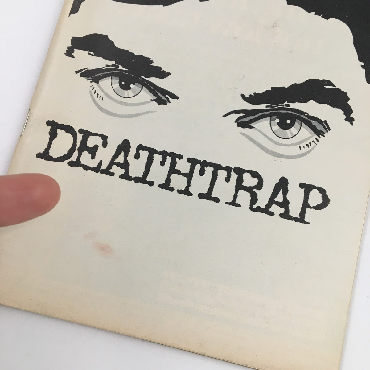 Close-up of the 1978 Playbill The Music Box Present John Wood in Ira Levin's Deathtrap, highlighting the title 'DEATHTRAP' and the expressive eyes from the cover design.