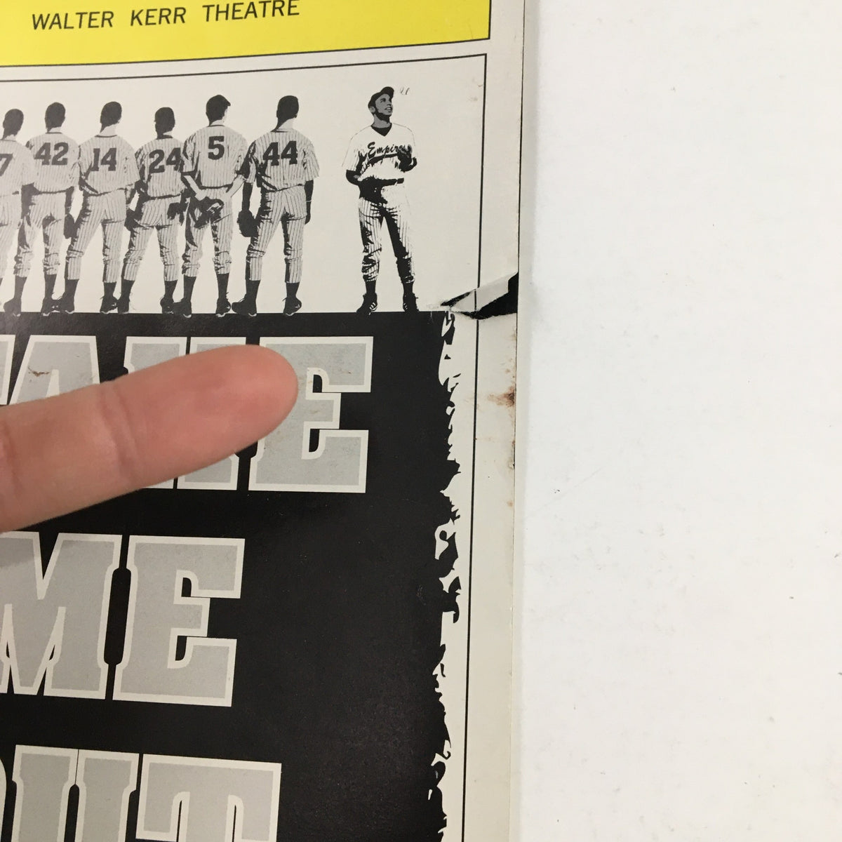 Close-up view of the 2003 Playbill for Take Me Out, showing a finger pointing at the edge with minor wear, highlighting its vintage condition.