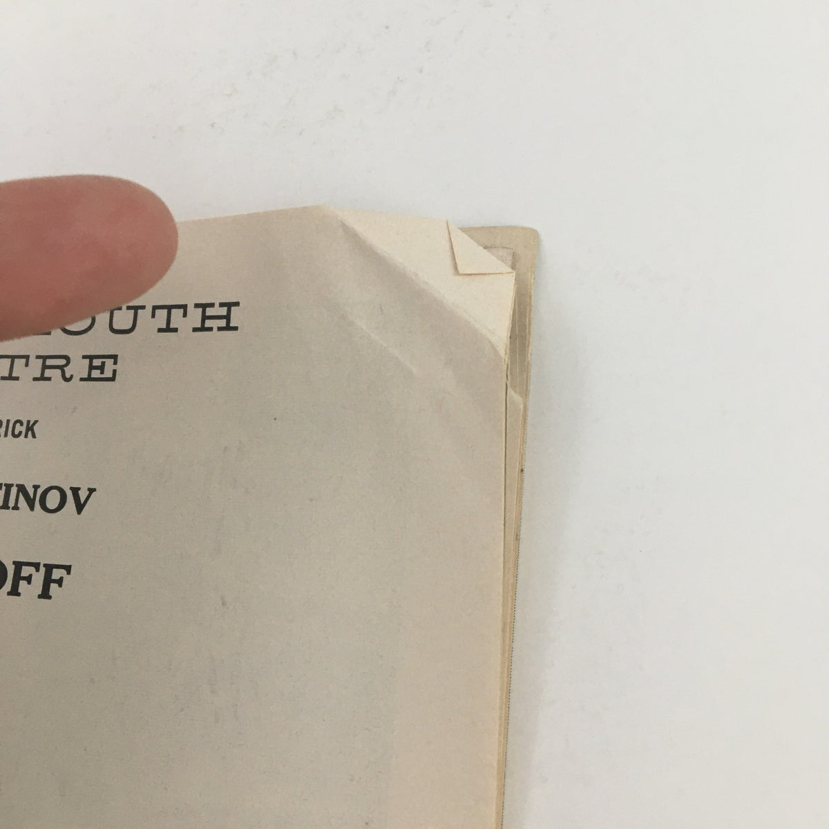 Close-up image of the 1957 Playbill for Romanoff and Juliet, highlighting a corner fold and finger pointing at the page.