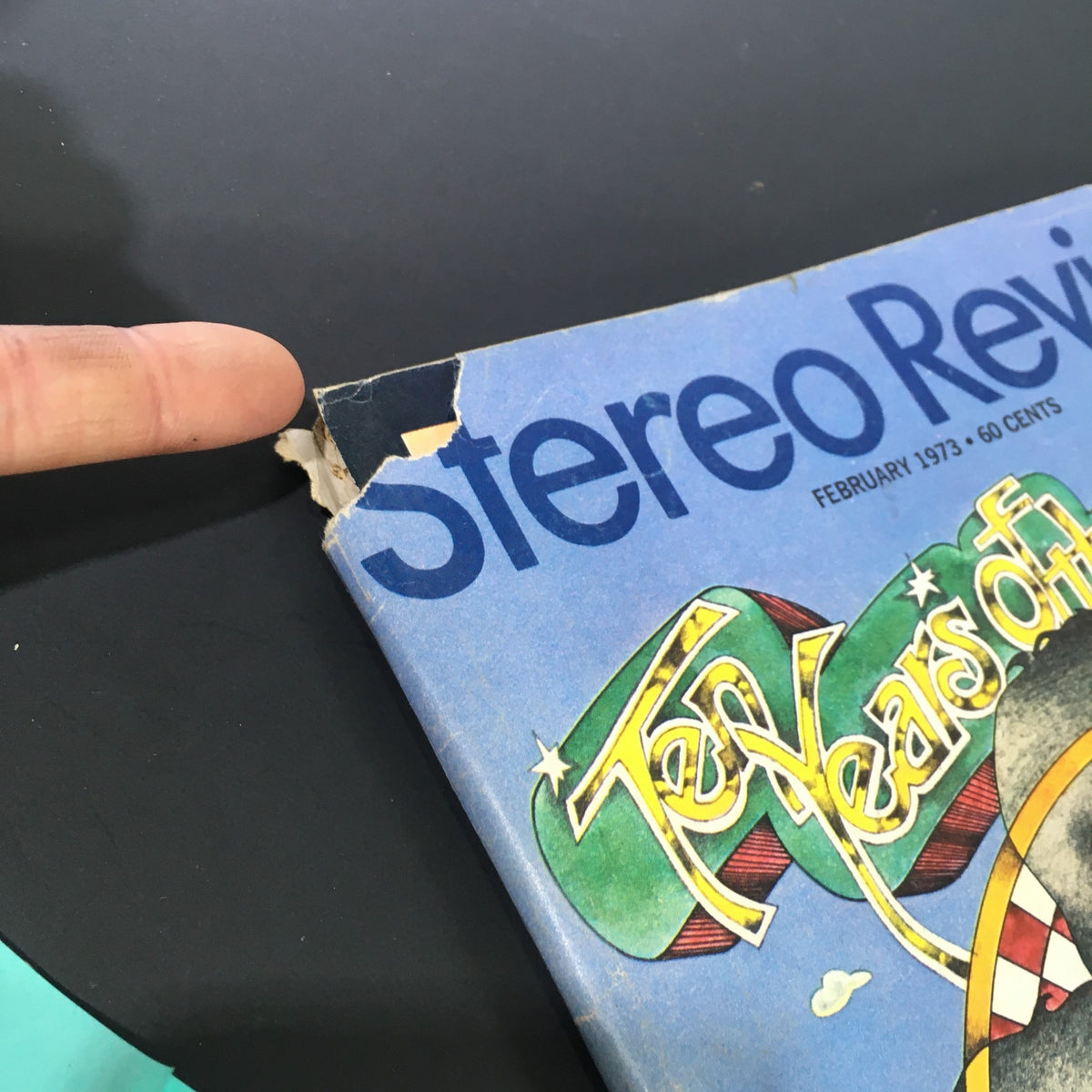 Close-up of the top edge of the VTG Stereo Review Music Magazine from February 1973, highlighting a small torn corner and wear on the cover of 'Ten Years of The Beatles' issue.