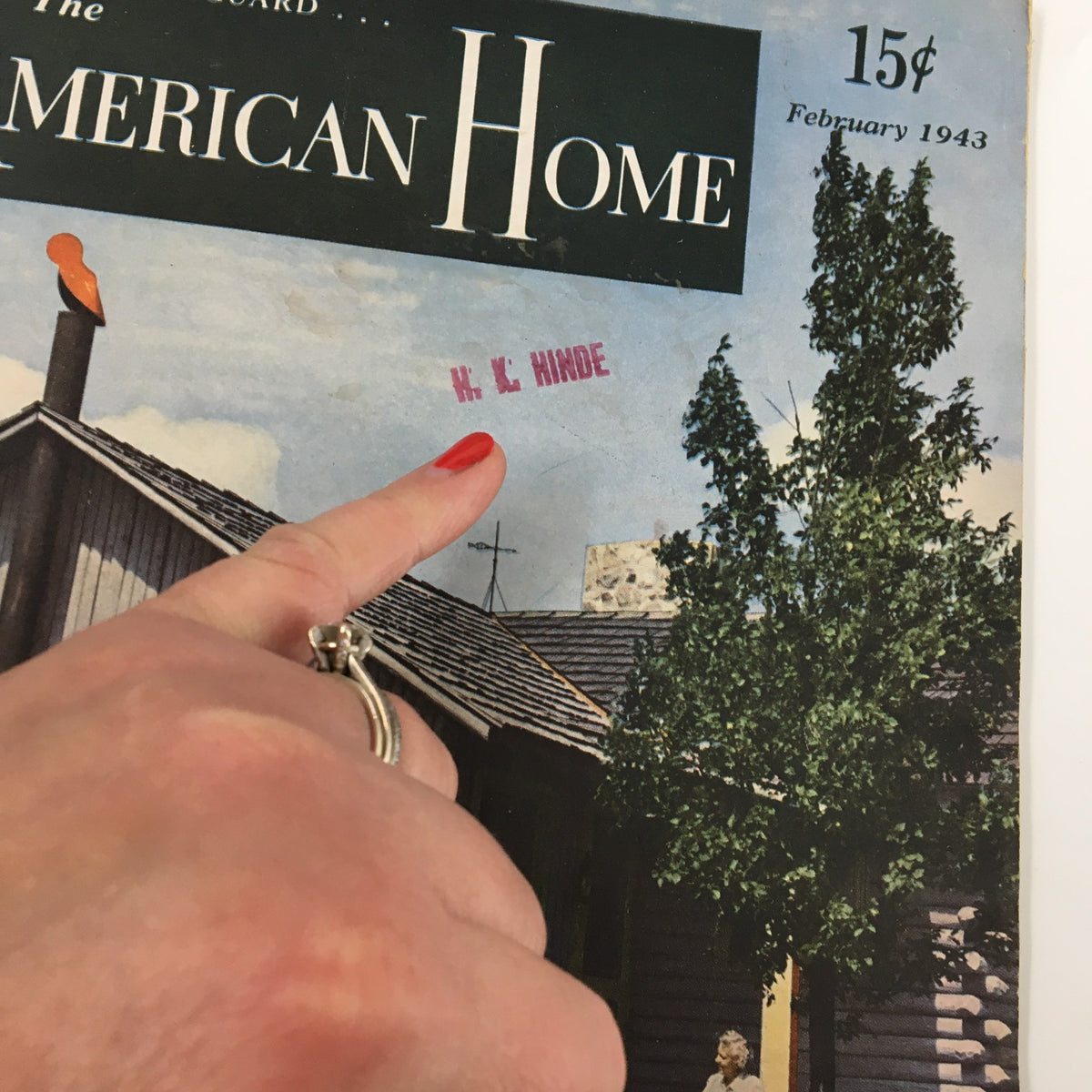 Cover of the February 1943 issue of The American Home Magazine featuring a pink label and a person pointing at it.