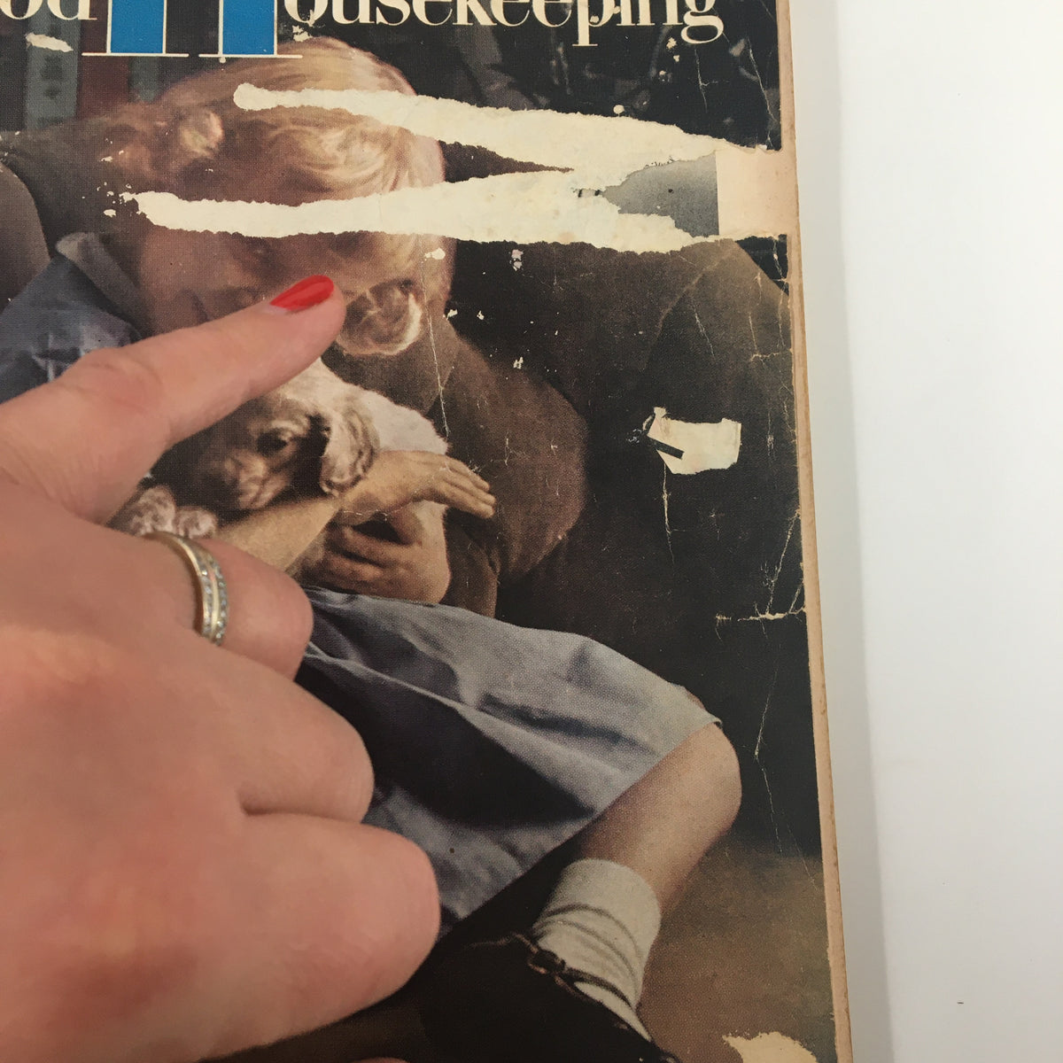 Close-up of the cover of the Vintage May 1956 Good Housekeeping magazine, highlighting a girl with a puppy and wear marks that add character to this collectible item.