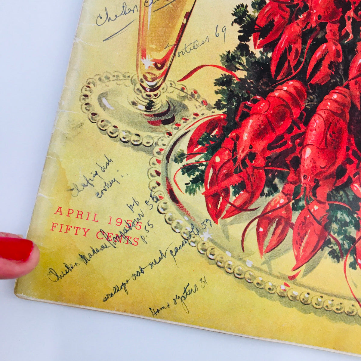 Detail of the bottom section of Gourmet Magazine April 1955 Vol 15 #4 cover, showcasing handwritten annotations and the magazine's publish date.