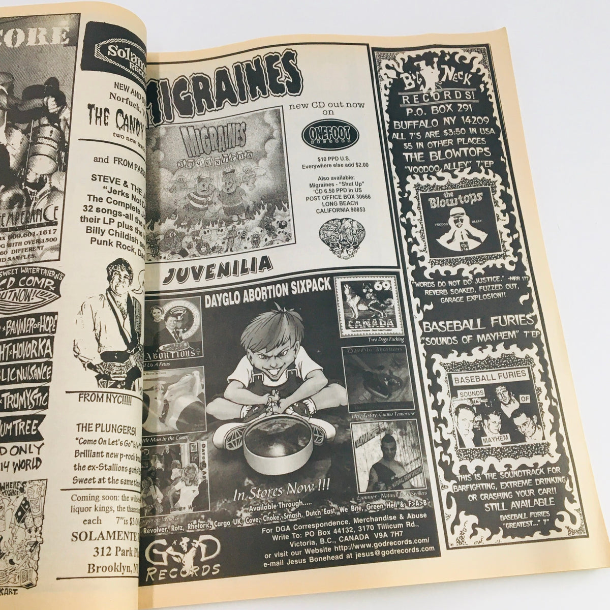 Page from Maximum RocknRoll Magazine August 1998 #183 featuring advertisements for bands including 'Juvenilia' and 'Dayglo Abortions', highlighting the punk rock scene.