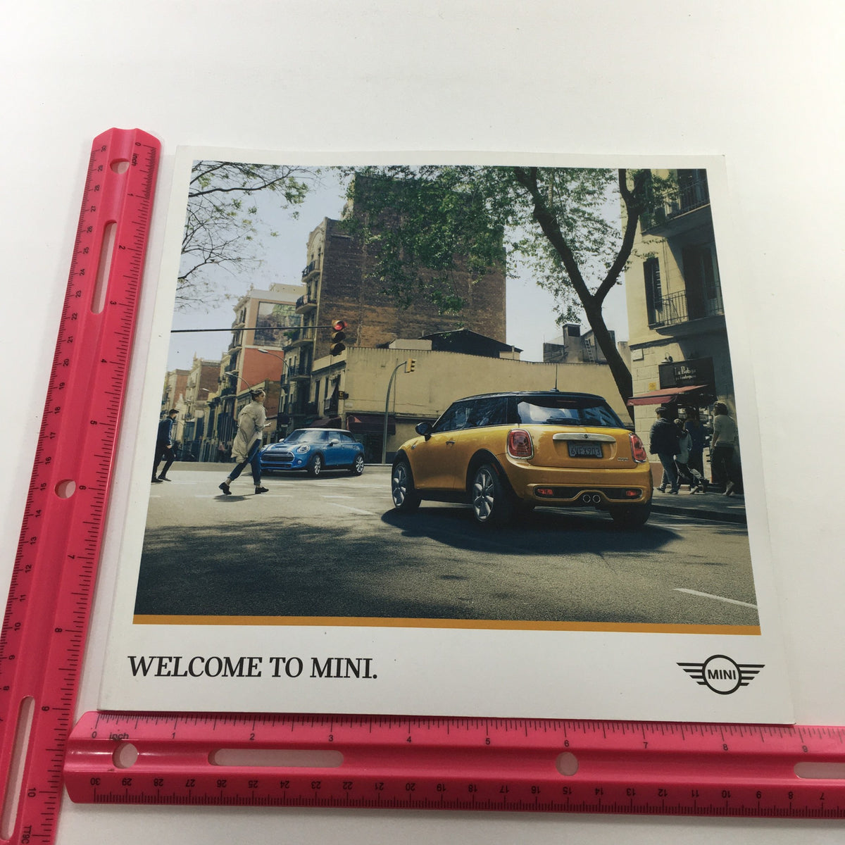 2016 Mini Cooper Motor The Spectrum Colors Dealership Car Auto Brochure Catalog image with a Mini Cooper parked on a street, showcasing its stylish design and welcoming ambiance.