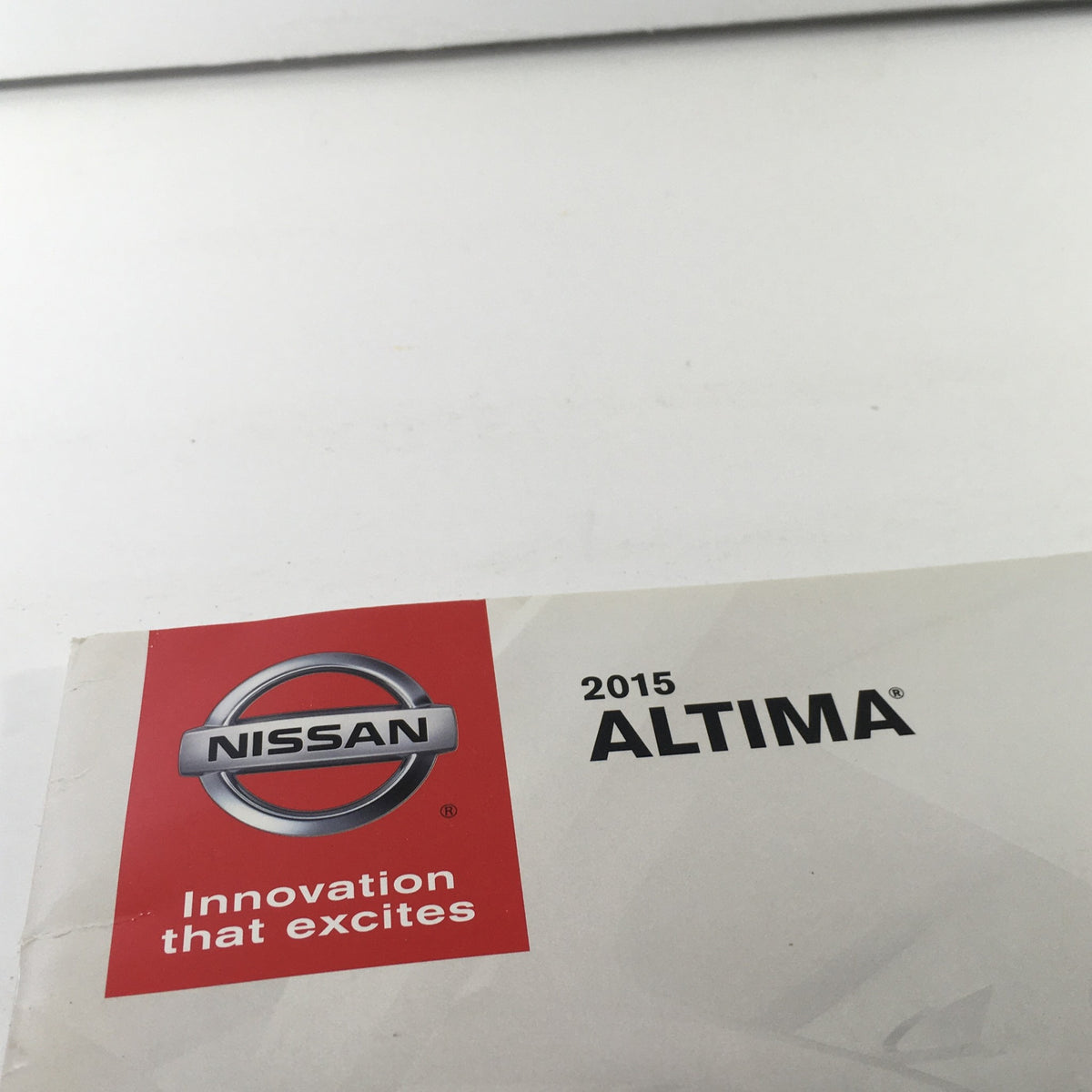 Close-up of the logo on the 2015 Nissan Altima Sedan Dealership Car Auto Brochure Catalog emphasizing 'Innovation that excites' tagline.