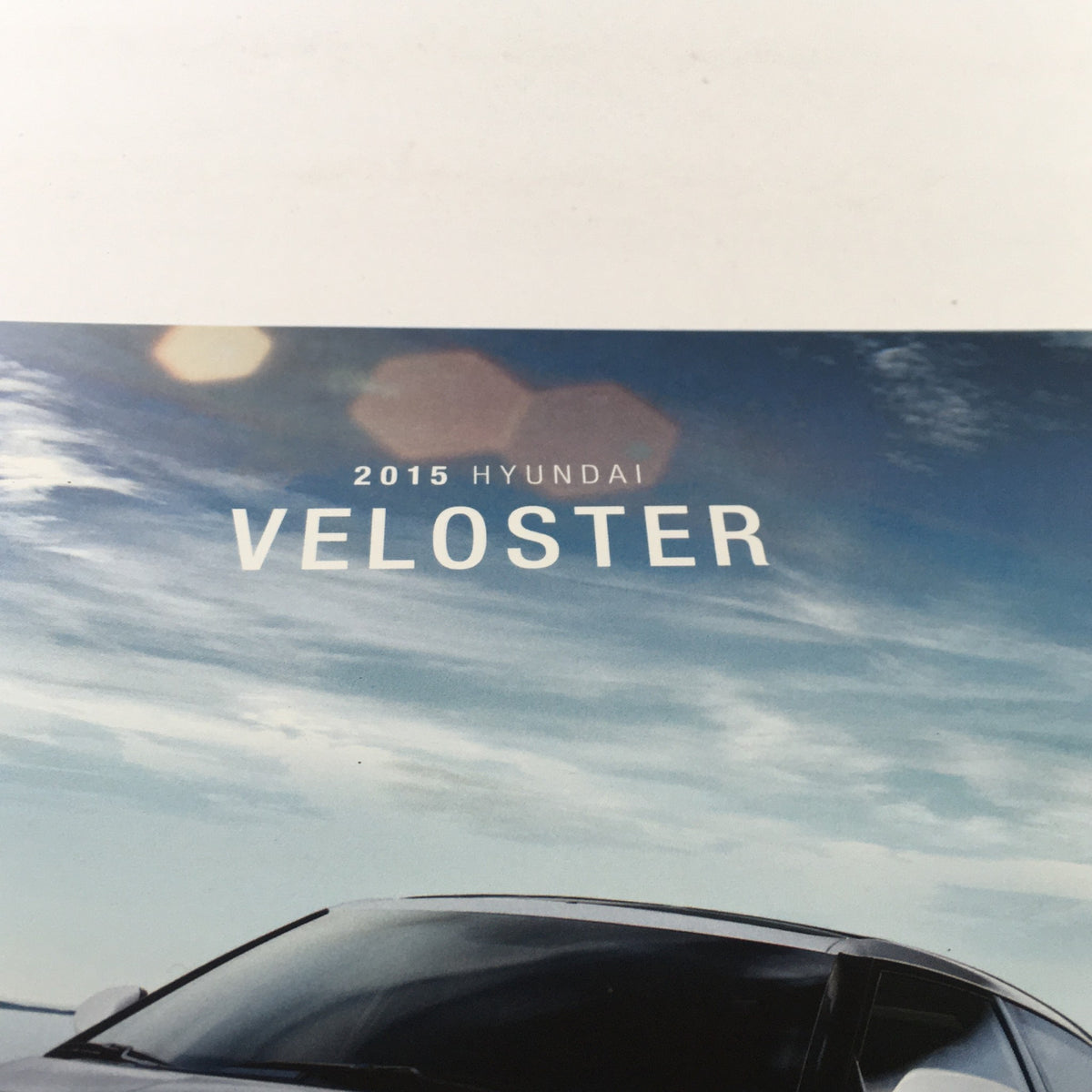 Close-up of the 2015 Hyundai Veloster title on the dealership car brochure, highlighting the model name.