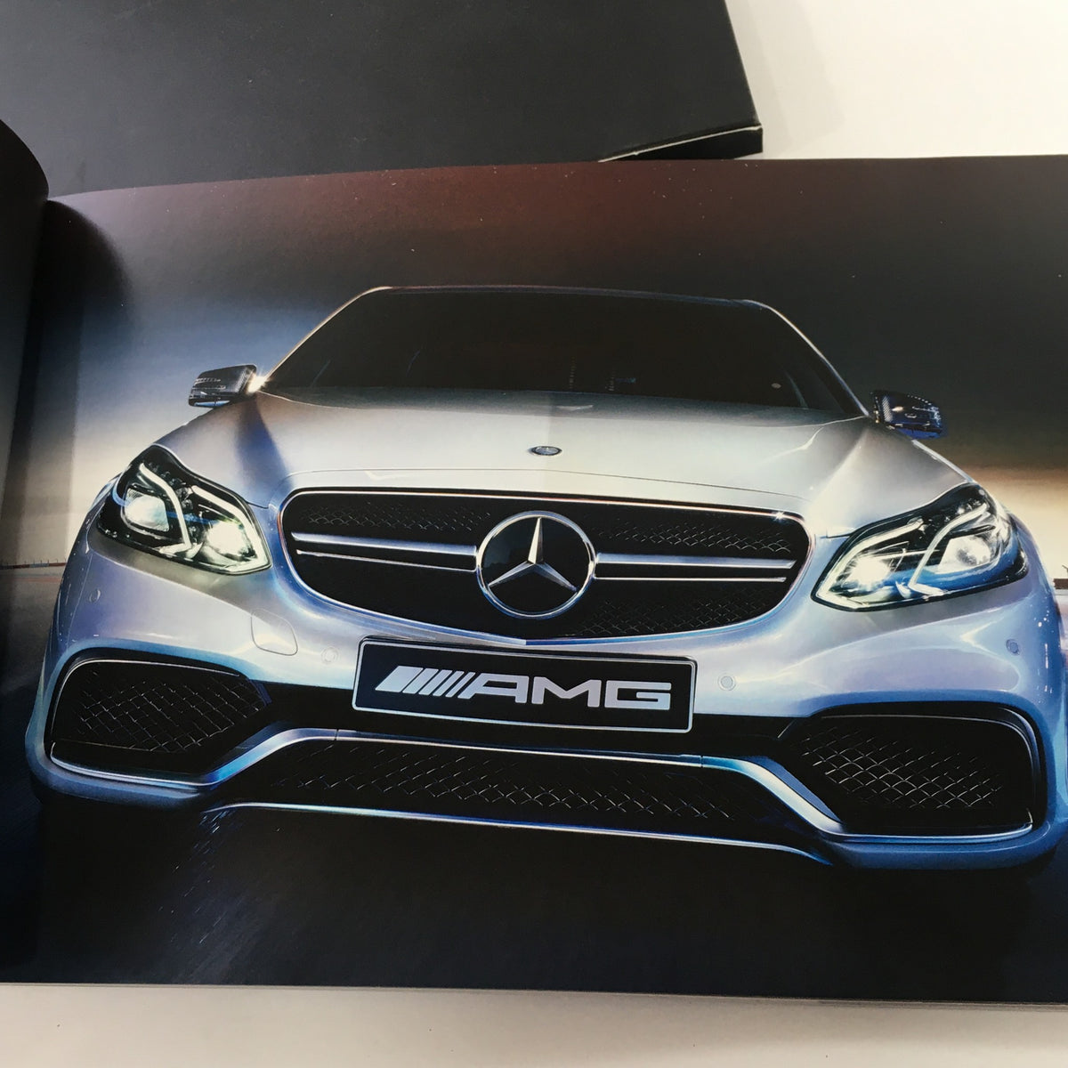 Image of a front view of a silver Mercedes-AMG vehicle from the 2013 Mercedes-Benz AMG Portfolio Dealership Car Auto Brochure Catalog emphasizing its design and AMG branding.