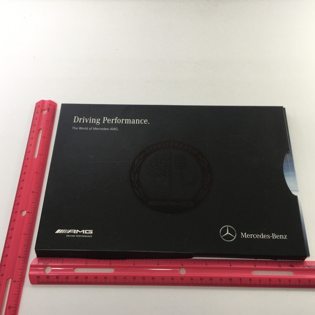 2013 Mercedes-Benz AMG Portfolio Dealership Car Auto Brochure Catalog shown with a ruler for size reference, highlighting the sleek black design.