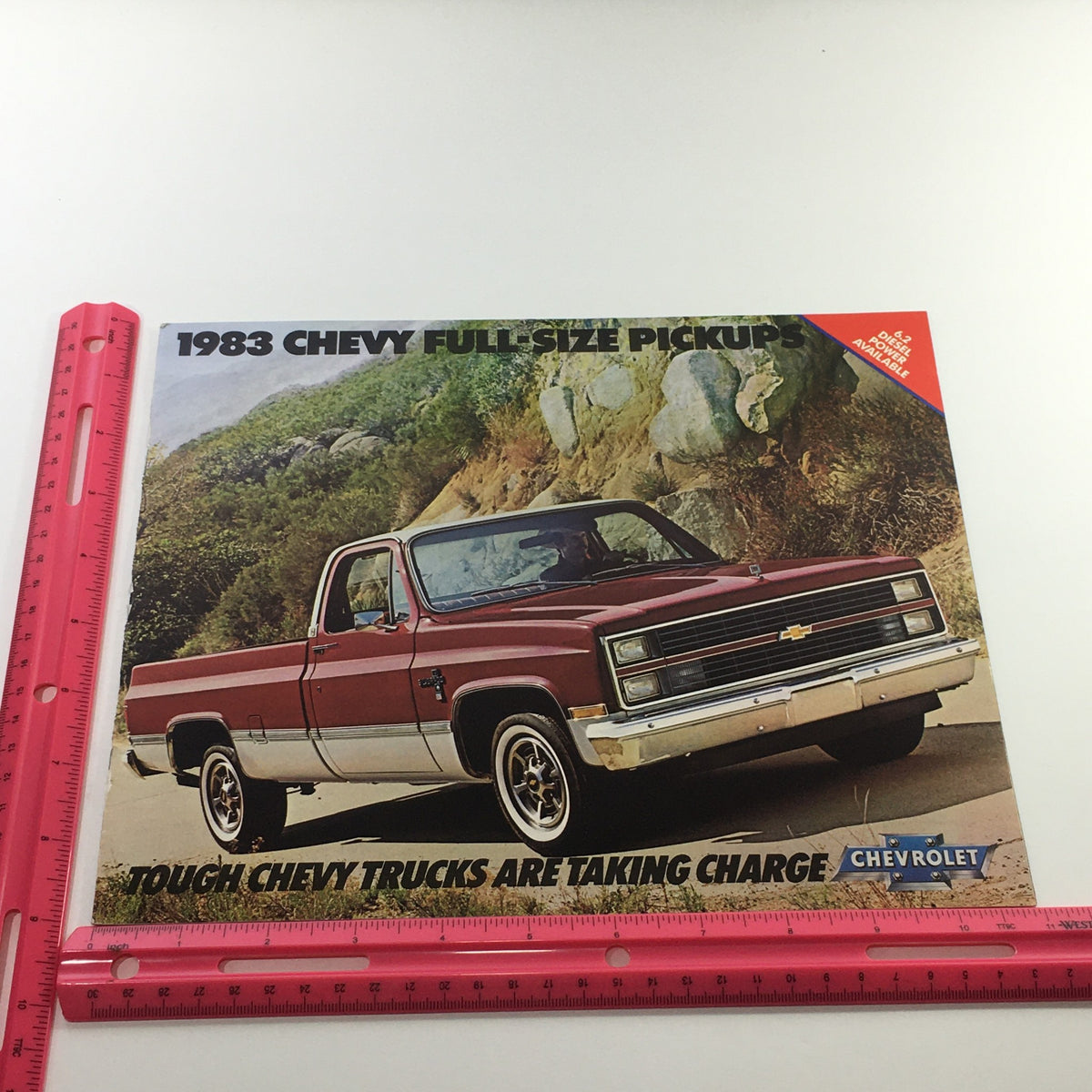 1983 Chevrolet Full-Size Pickup Dealership Car Auto Brochure Catalog with a red Chevy truck in an outdoor setting, overlaid with measurement tools for detail.