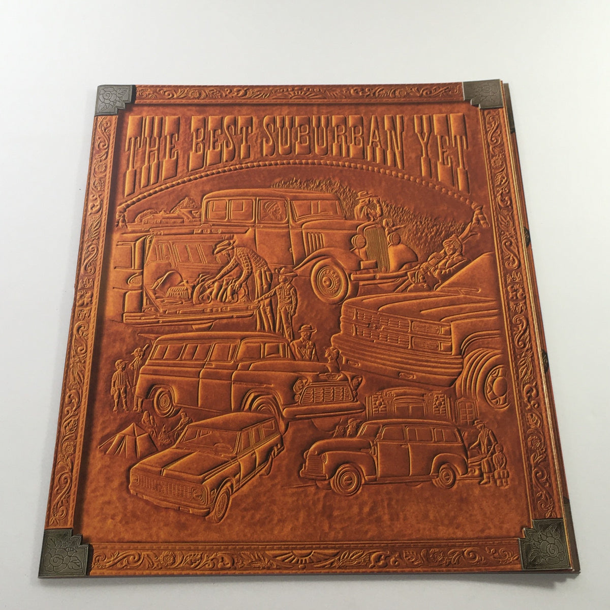 Cover of the 2000s Chevrolet Chevy Suburban Dealership Car Auto Brochure Catalog featuring embossed illustrations of various Suburban models and off-road scenes.
