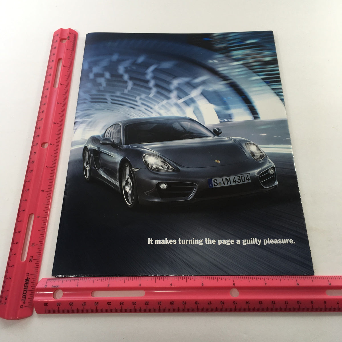 2013 Porsche Cayman Code Dealership Car Auto Brochure Catalog featuring a sleek black Porsche Cayman in a dynamic tunnel setting, emphasizing luxury and performance.