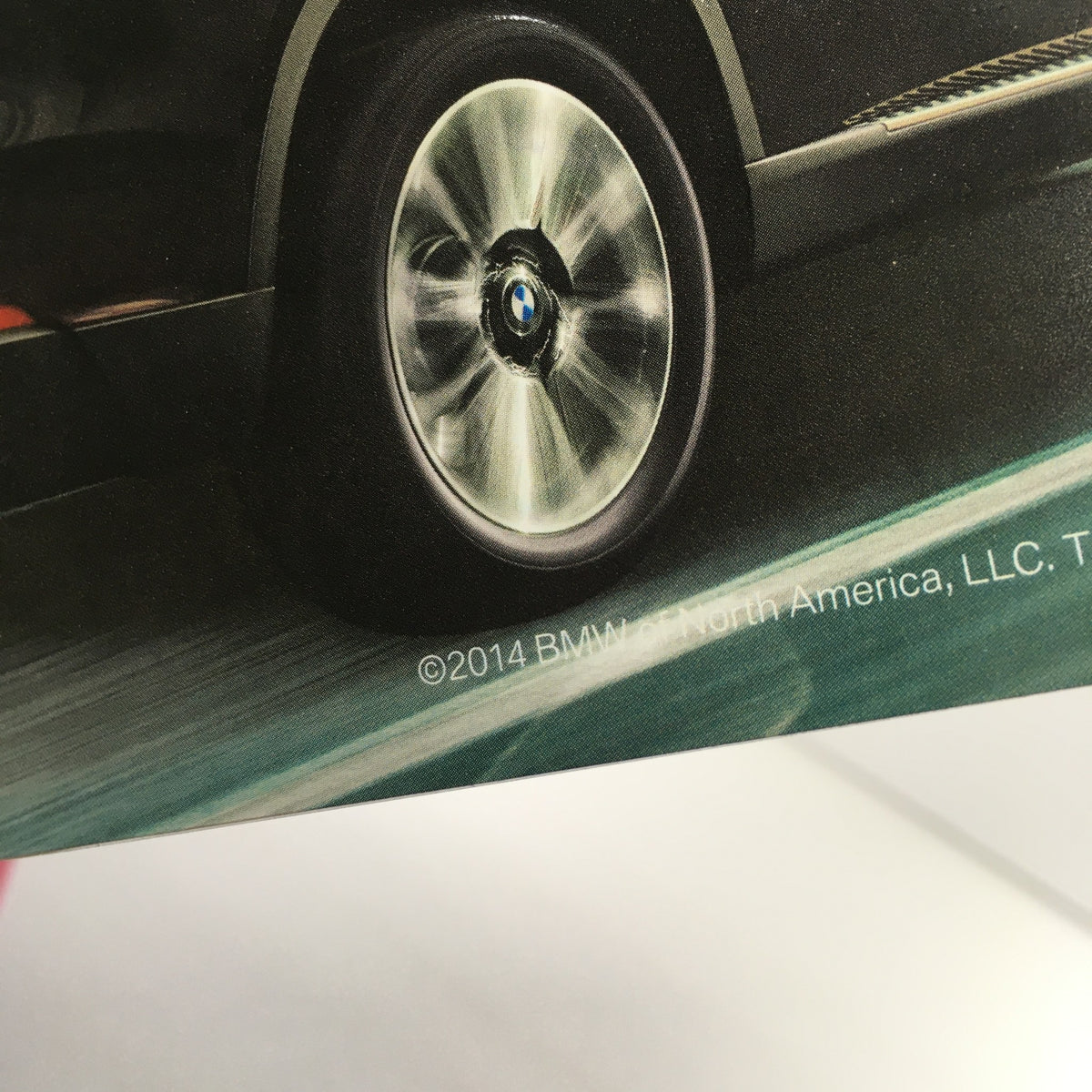 Close-up of the wheel of the 2014 BMW X-5 seen in the dealership car auto brochure, showcasing its sleek design and performance quality.