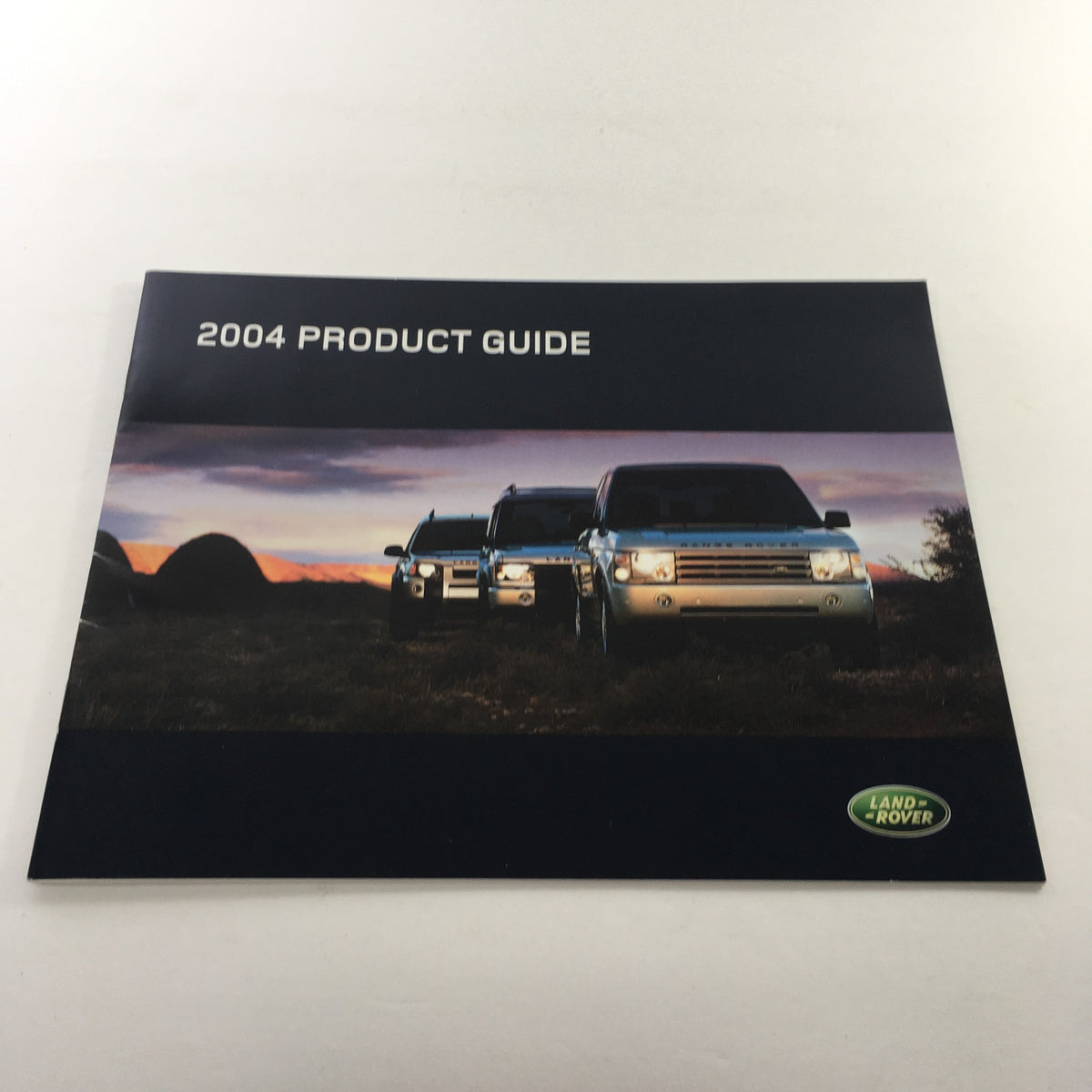 Cover of the 2004 Land Rover Product Guide showcasing three Land Rover vehicles against a scenic backdrop.