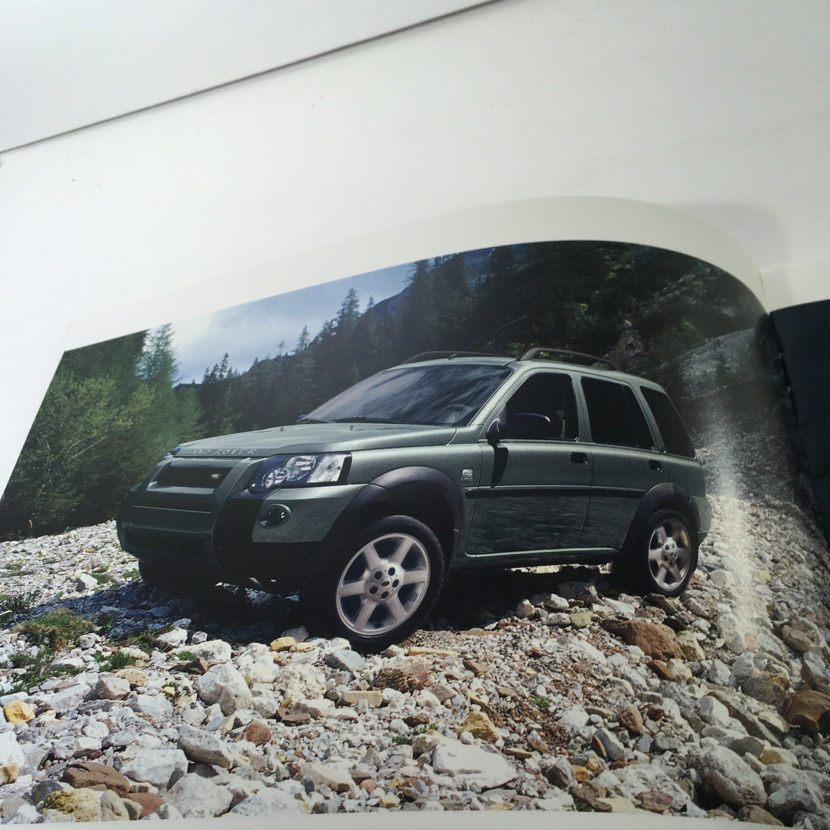 Interior page of the 2004 Land Rover Product Guide featuring a green Land Rover vehicle parked on rocky terrain.