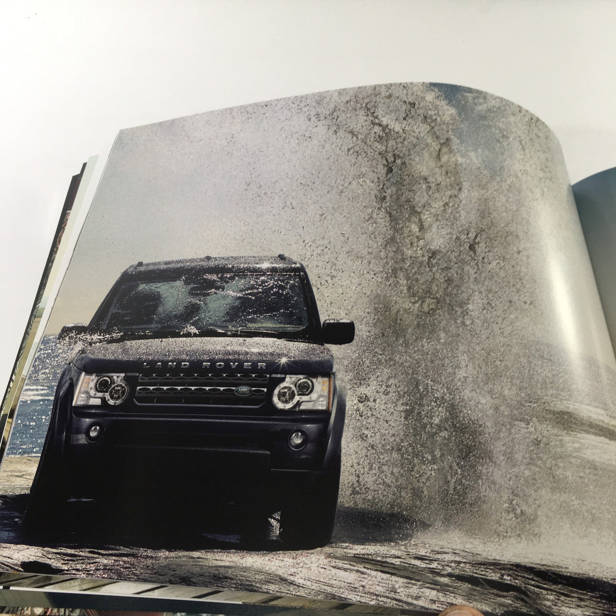 Action shot of a 2010 Land Rover LR-4 driving through water, featured in the dealership brochure catalog.