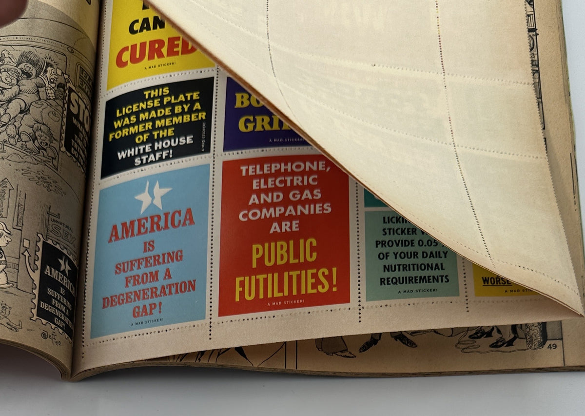 Image showing a page from MAD Magazine Super Special No. 16, displaying the MAD-Hesives stickers with satirical statements. These stickers highlight the humorous and critical tone of the magazine.