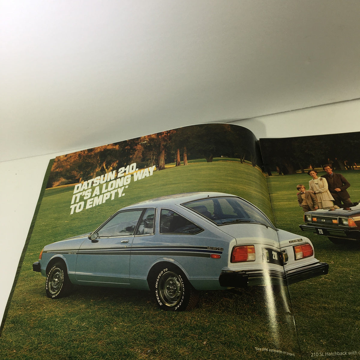 Page from the 1980 Datsun Quality Shows Dealership Car Auto Brochure Catalog featuring the Datsun 210 model, showcasing its design in a park environment.
