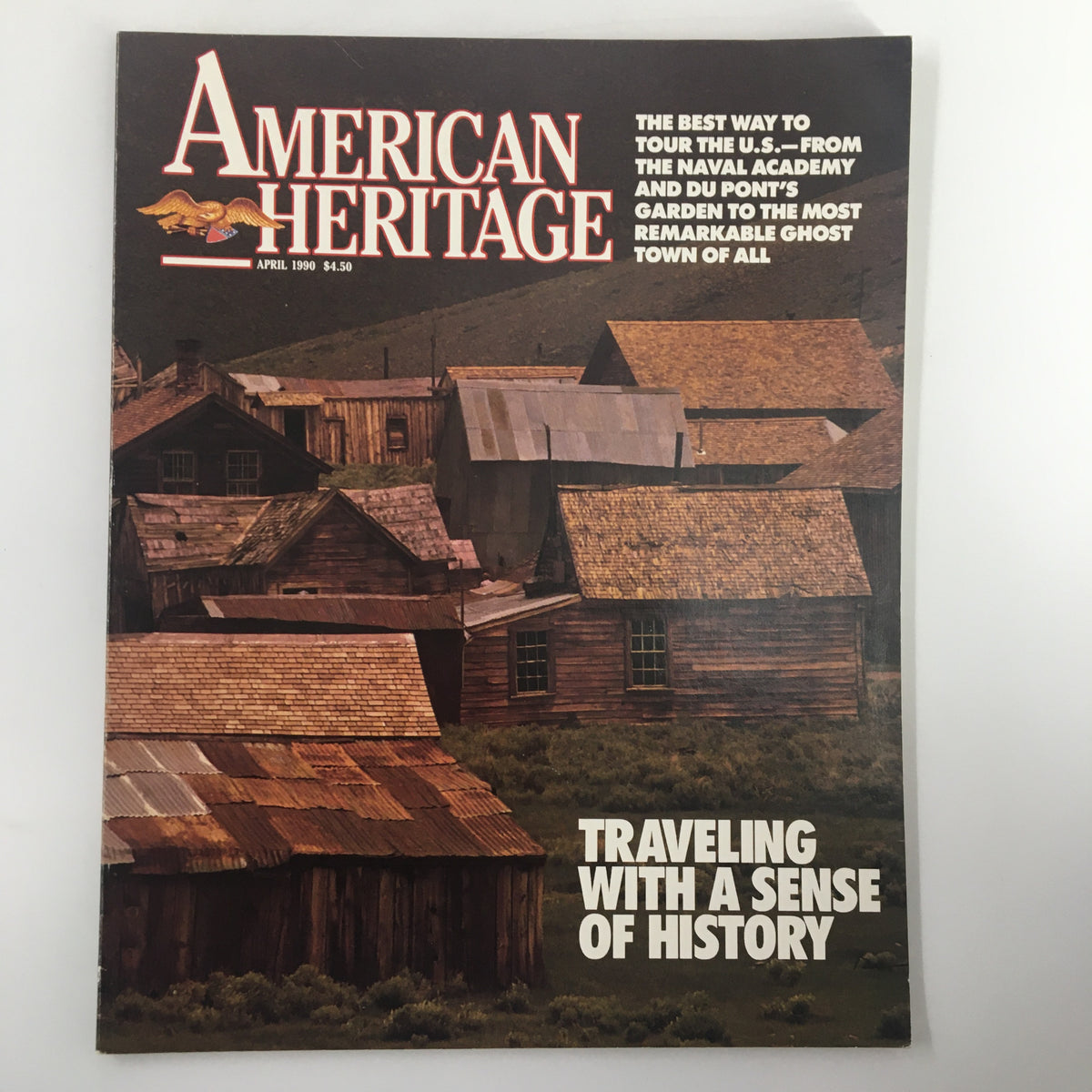 Cover of American Heritage Magazine, April 1990, showcasing the theme 'Traveling with a Sense of History.' The image features an illustration of historical wooden buildings, emphasizing American cultural heritage and exploration.