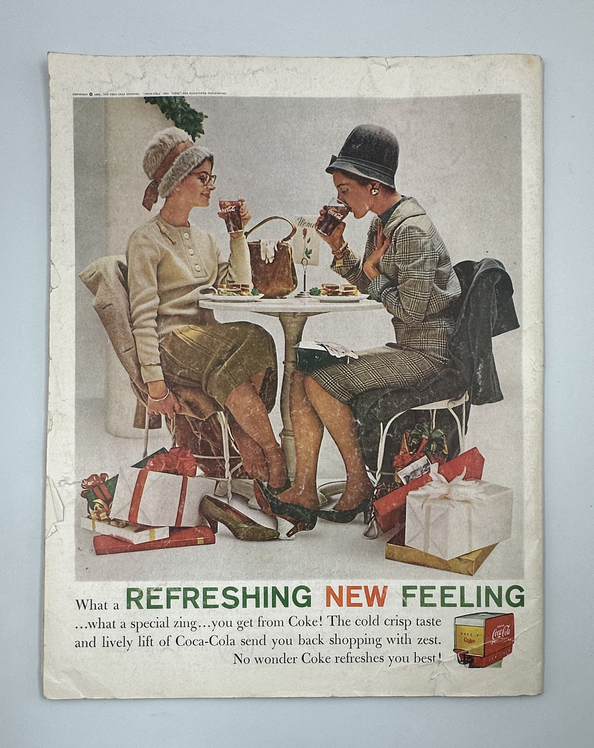 Vintage advertisement in the Saturday Evening Post Magazine from November 18, 1961, showcasing two women enjoying Coca-Cola at a café table, emphasizing a refreshing feeling.