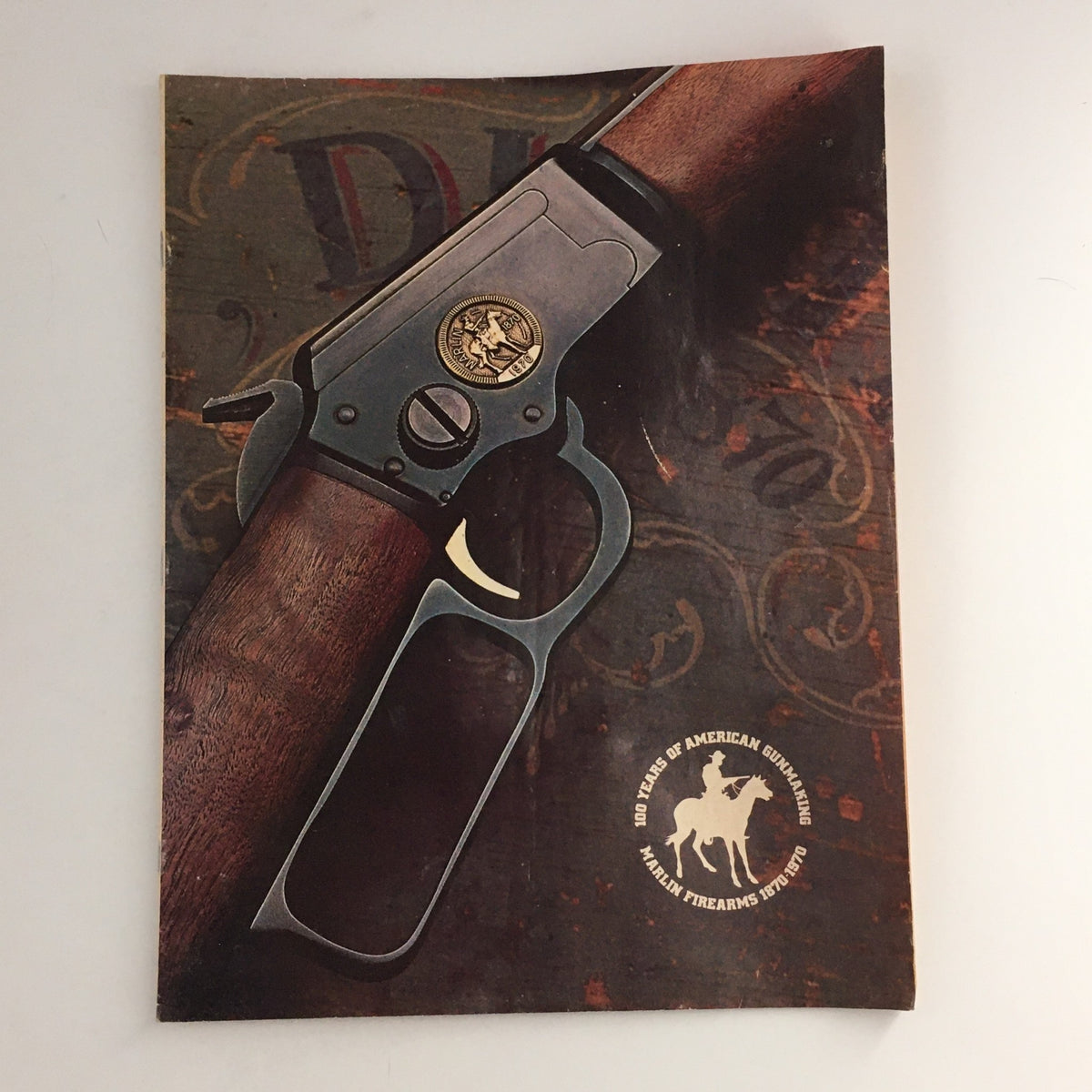 Cover page of '100 Years of American Gunmaking Marlin Firearms 1870-1970' featuring a detailed illustration of a Marlin firearm with wood and metal textures.