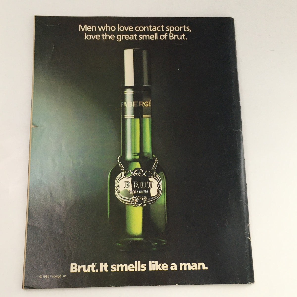 WWF Magazine December 1986 advertisement for Brut cologne, featuring a bottle with the tagline emphasizing its appeal to sports enthusiasts, aligning with the wrestling lifestyle.
