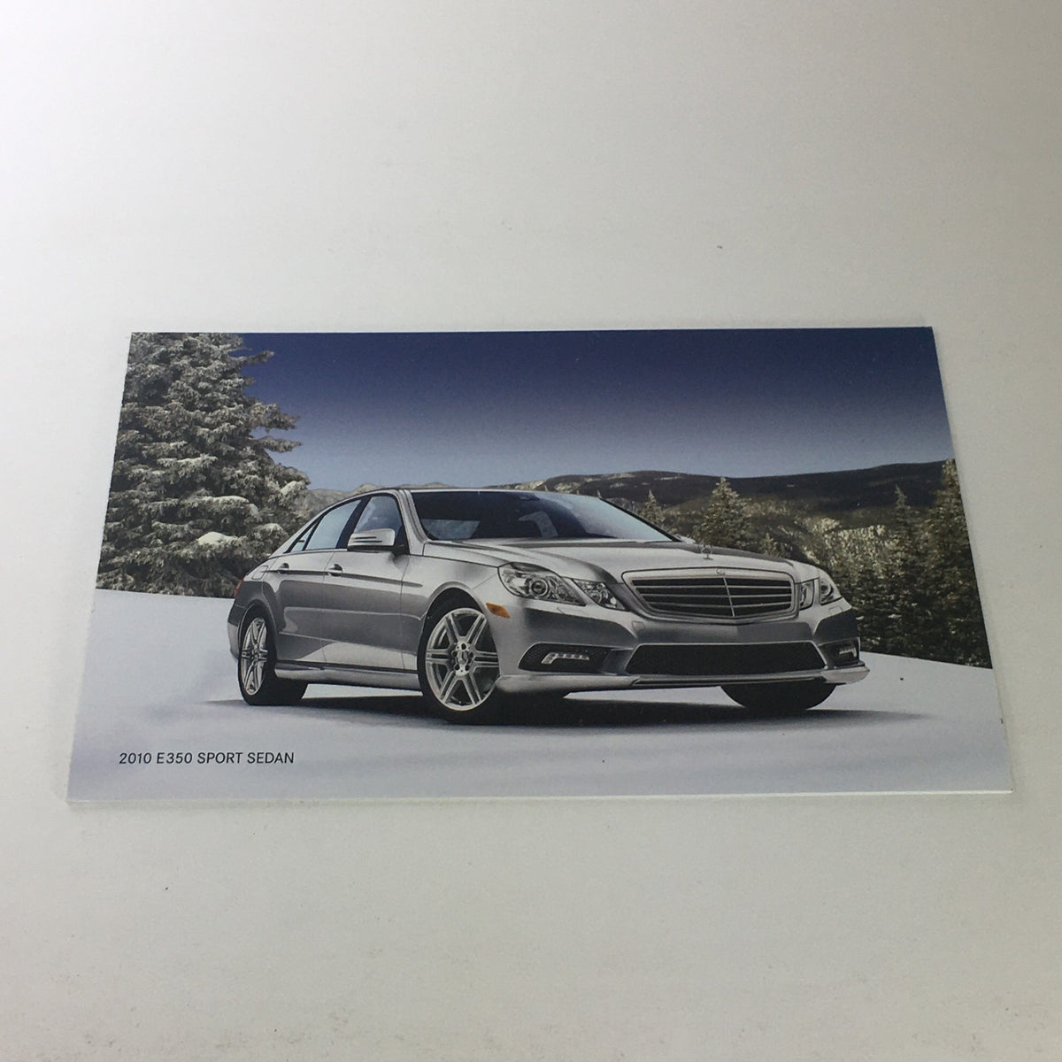 2010 Mercedes-Benz Financial E-350 Sport Sedan Dealership Catalog Brochure image showcasing the silver E-350 Sport Sedan parked on snow, highlighting its sleek design and sporty features.